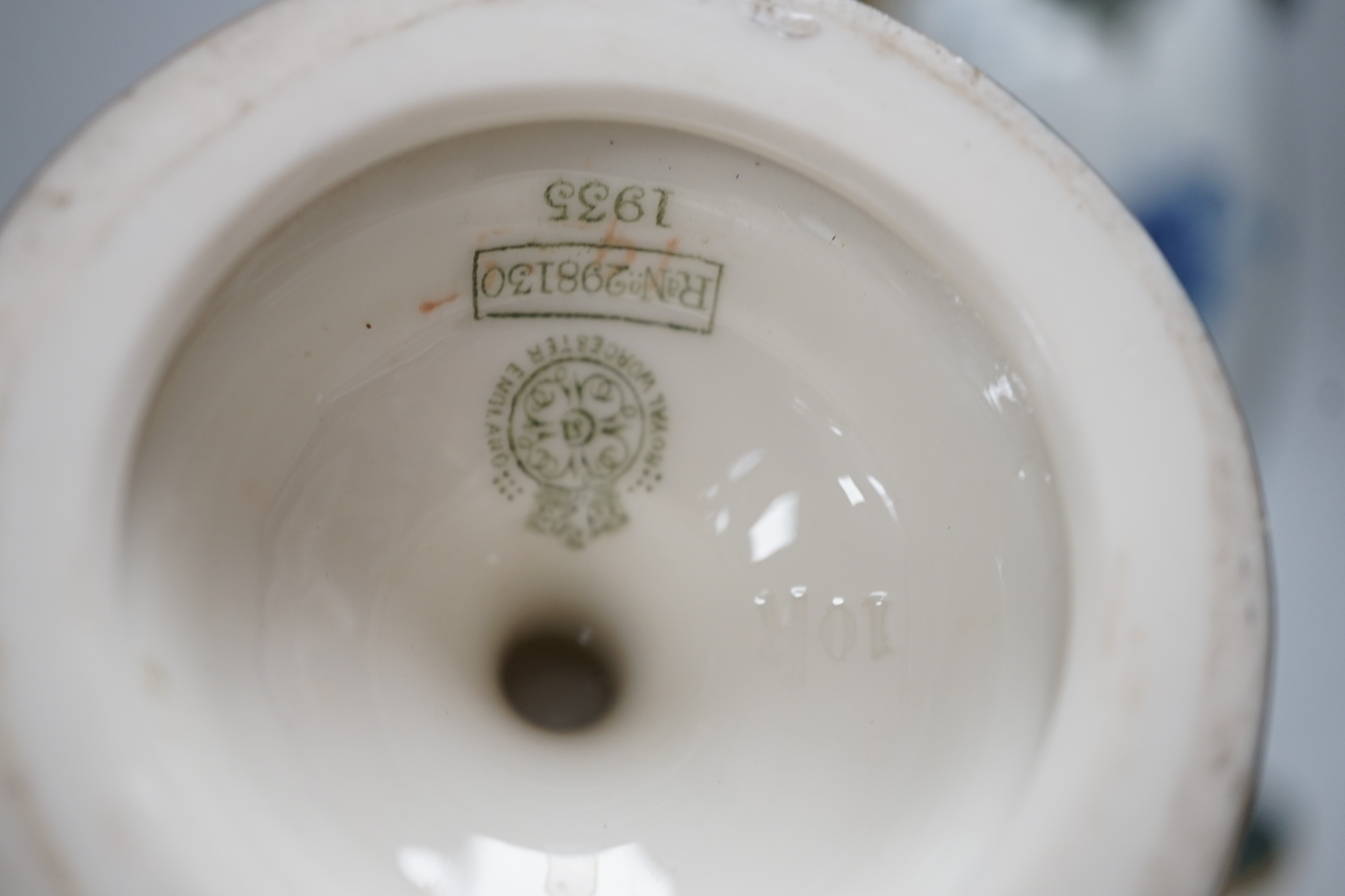 Three Royal Worcester pedestal vases, each of ovoid form and supported on circular pedestal feet, two are decorated with flowers and thistles, the other depicting a rural landscape within a gilt foliate C scroll cartouch